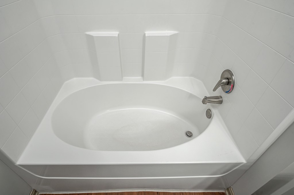 A white bathtub with a silver faucet and a silver handle.